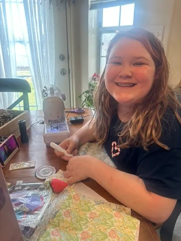Ava smiling while working on a creative project at the table